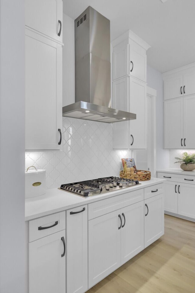 3041 Robeson Trce, Johns Island, SC 29455 - kitchen featuring wall chimney range hood, white cabinetry, light countertops, decorative backsplash, and light wood-type flooring