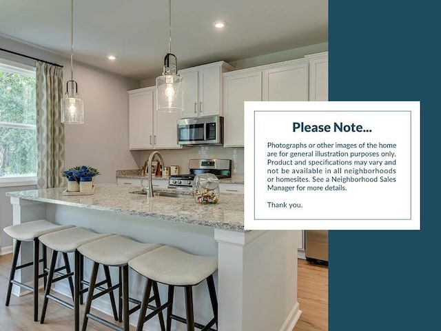 3041 Robeson Trce, Johns Island, SC 29455 - kitchen featuring appliances with stainless steel finishes, a breakfast bar area, white cabinetry, light stone counters, and recessed lighting
