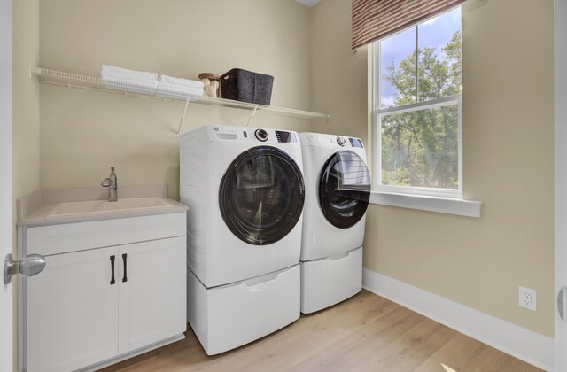 3041 Robeson Trce, Johns Island, SC 29455 - laundry area featuring washing machine and clothes dryer, light wood finished floors, cabinet space, and baseboards