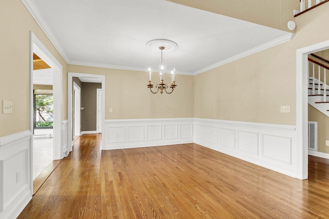 empty room featuring hardwood / wood-style floors, an inviting chandelier, and ornamental molding