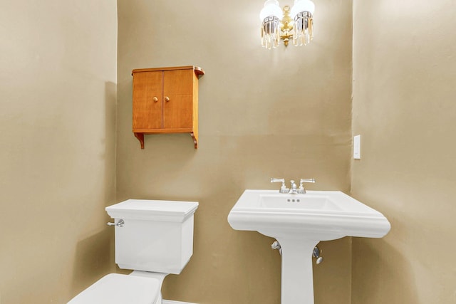 bathroom with toilet and an inviting chandelier