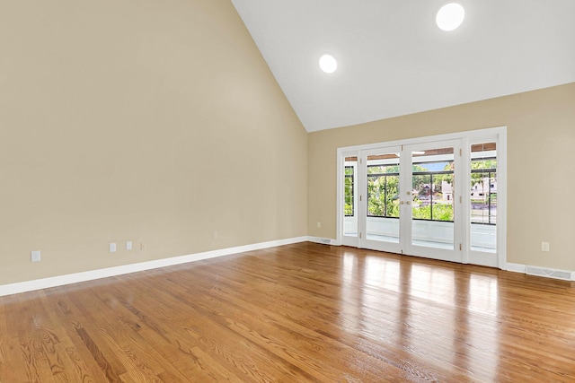 empty room featuring high vaulted ceiling, light wood-type flooring, and french doors