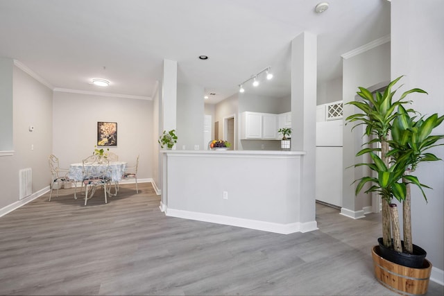 interior space with visible vents, light wood-style flooring, baseboards, and ornamental molding