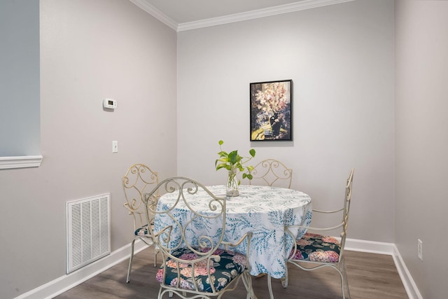 dining area featuring visible vents, crown molding, baseboards, and wood finished floors