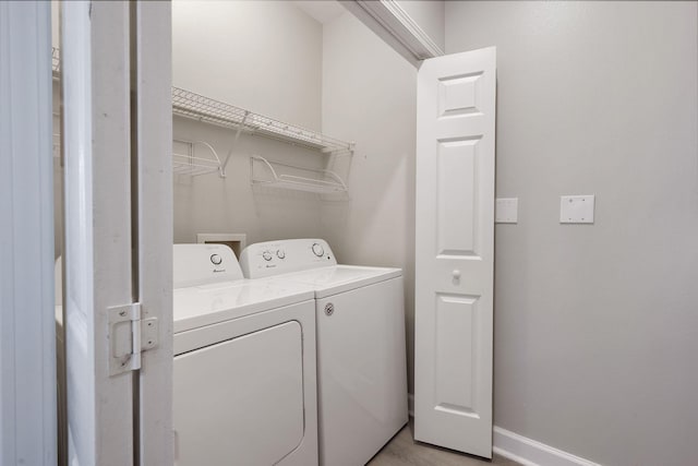 clothes washing area with laundry area, washing machine and dryer, and baseboards