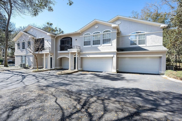 view of front of home featuring central air condition unit, stucco siding, driveway, a garage, and a balcony