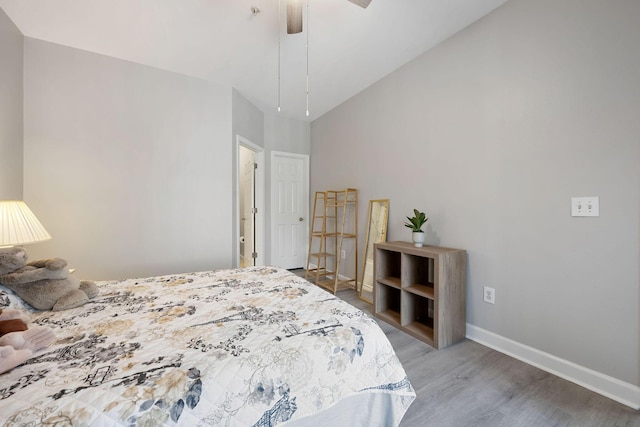 bedroom with a ceiling fan, wood finished floors, baseboards, and high vaulted ceiling