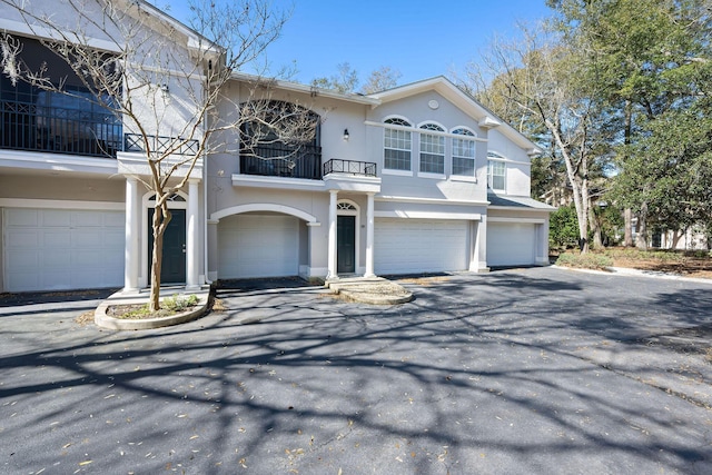 view of front of home with a balcony, stucco siding, driveway, and a garage