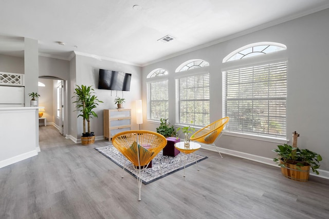 living area with visible vents, arched walkways, a healthy amount of sunlight, and wood finished floors