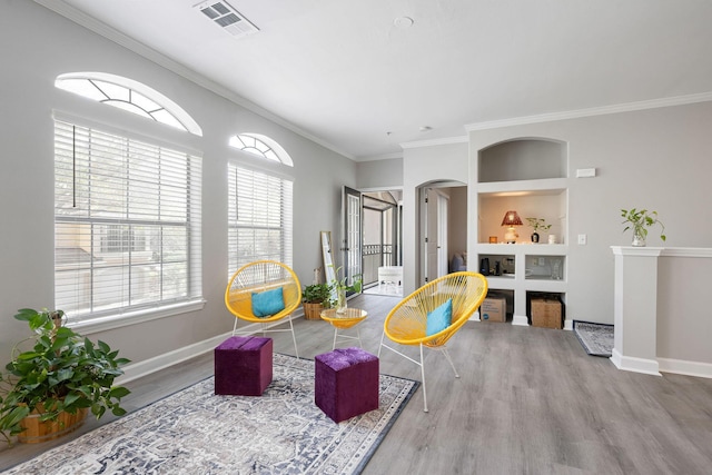 sitting room with visible vents, baseboards, built in features, wood finished floors, and arched walkways