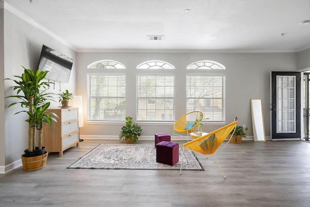 living area with plenty of natural light, wood finished floors, and crown molding