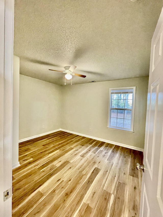 empty room with hardwood / wood-style floors, a textured ceiling, and ceiling fan