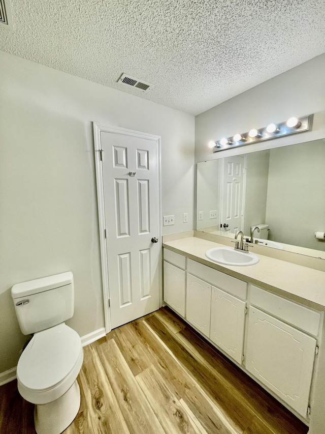 bathroom featuring hardwood / wood-style floors, vanity, toilet, and a textured ceiling