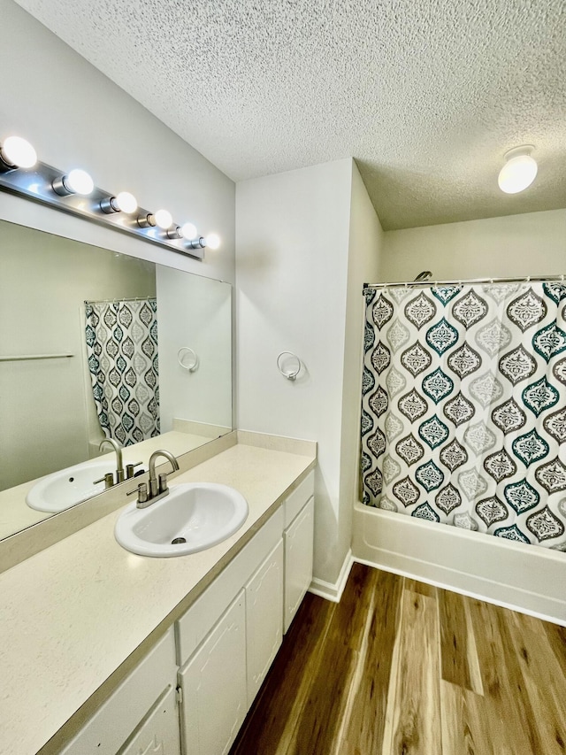 bathroom with vanity, bathtub / shower combination, a textured ceiling, and hardwood / wood-style flooring