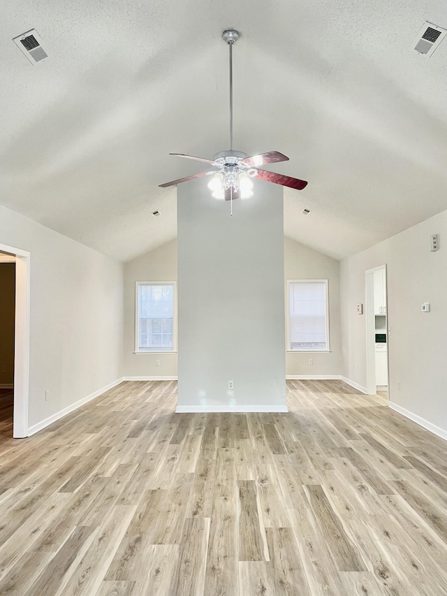 unfurnished living room with a textured ceiling, light hardwood / wood-style flooring, and vaulted ceiling