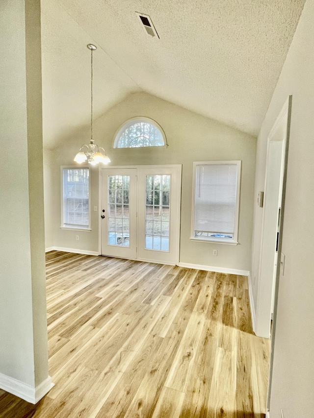 interior space featuring a notable chandelier, lofted ceiling, a textured ceiling, and light hardwood / wood-style flooring