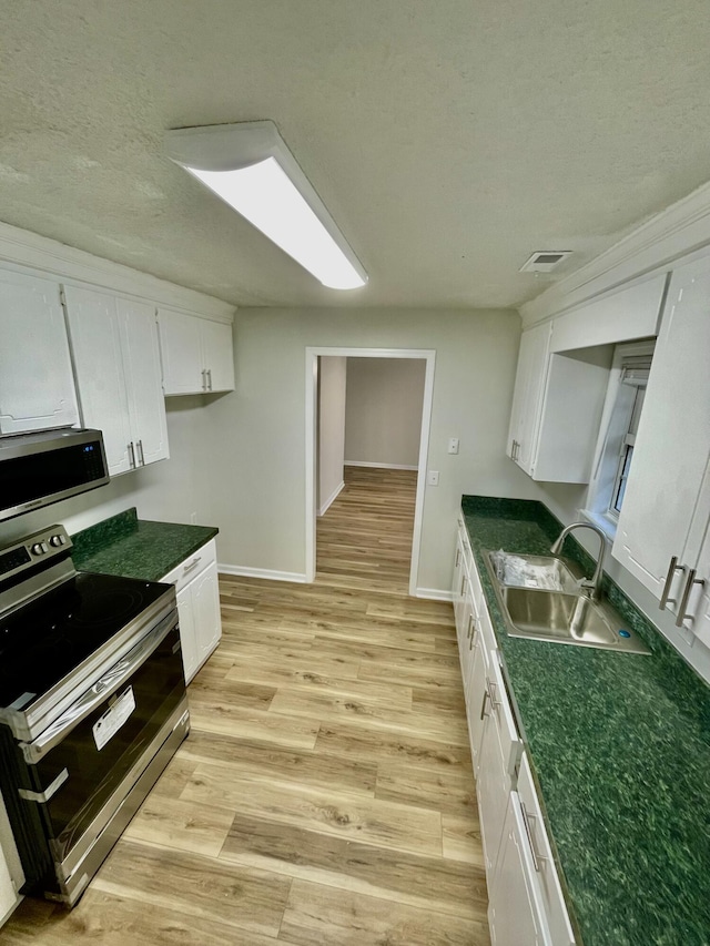 kitchen featuring white cabinets, appliances with stainless steel finishes, light hardwood / wood-style flooring, and sink