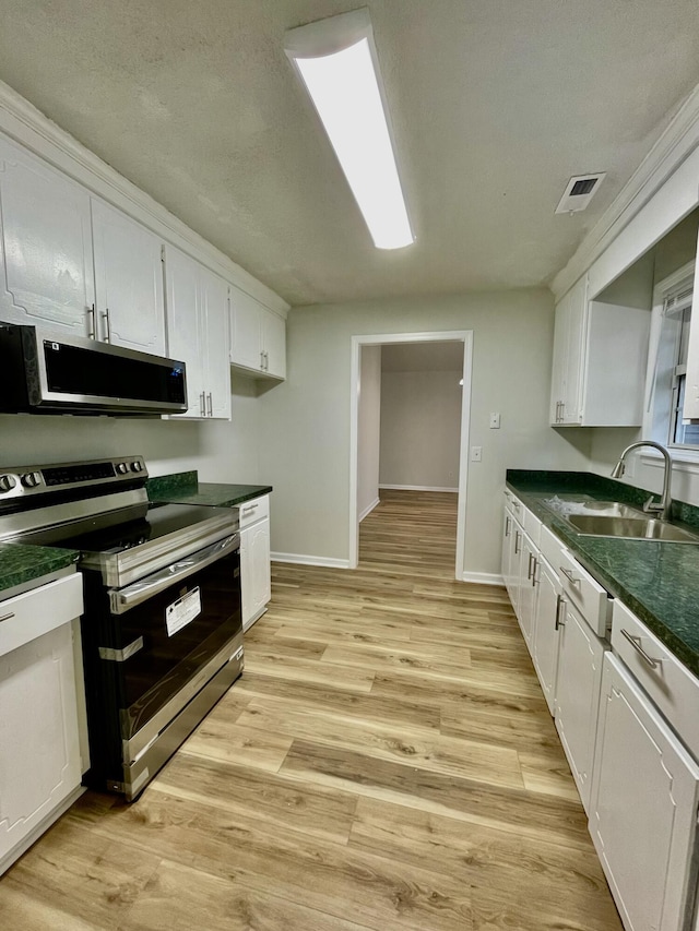 kitchen with light hardwood / wood-style floors, sink, white cabinetry, and stainless steel appliances