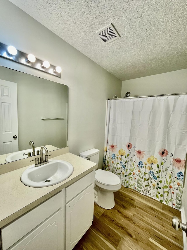 bathroom featuring toilet, vanity, a textured ceiling, and hardwood / wood-style flooring