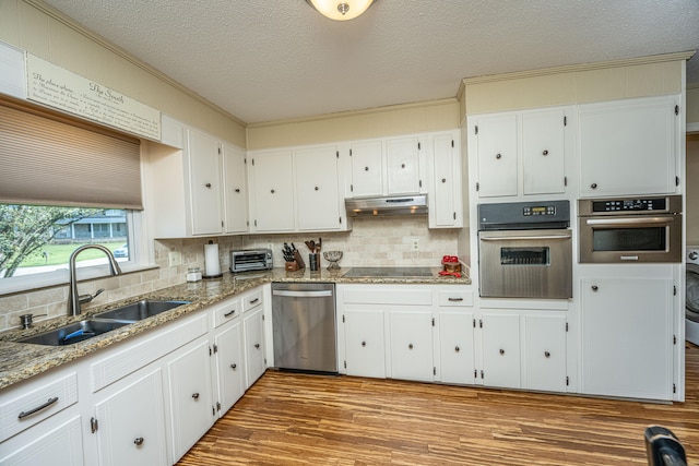 kitchen with appliances with stainless steel finishes, sink, hardwood / wood-style floors, and white cabinets