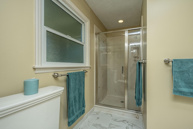 bathroom featuring a textured ceiling, toilet, and an enclosed shower