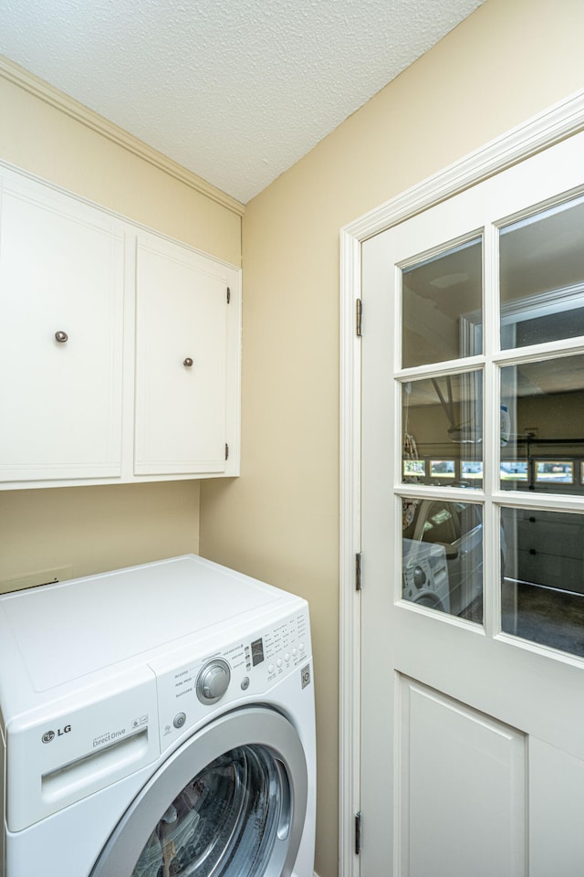 laundry area with cabinets, washer / clothes dryer, and a textured ceiling