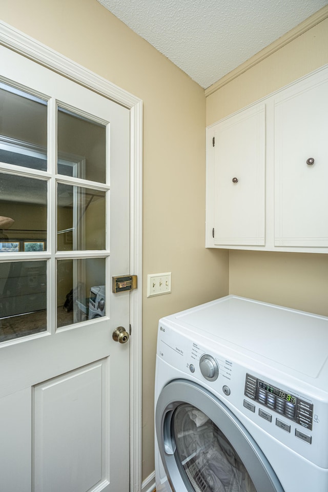 laundry room with washer / dryer, a textured ceiling, and cabinets