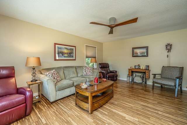 living room featuring ceiling fan, a textured ceiling, and light hardwood / wood-style flooring