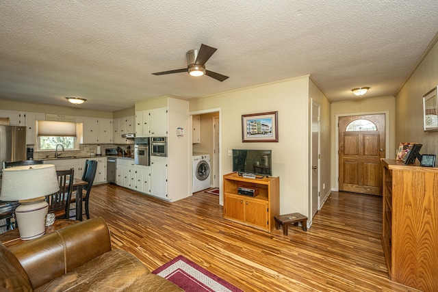 living room with washer / dryer, ceiling fan, a textured ceiling, light hardwood / wood-style flooring, and sink