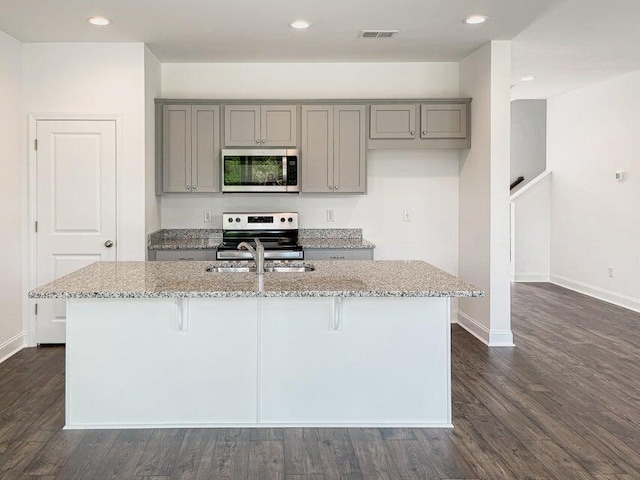 kitchen with stainless steel appliances, light stone countertops, gray cabinetry, and visible vents