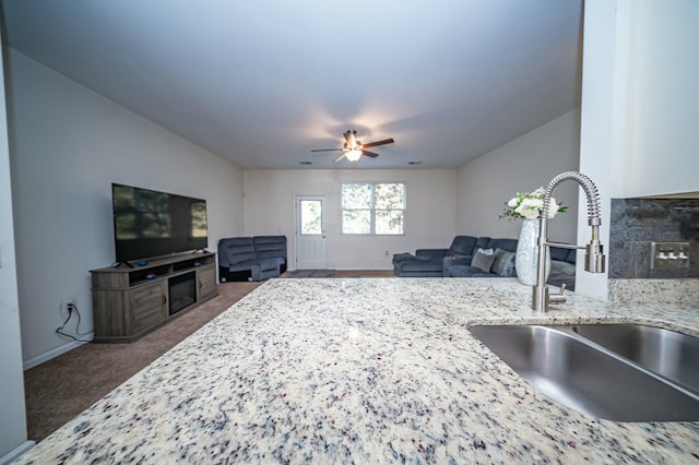 interior space featuring ceiling fan, sink, and dark colored carpet