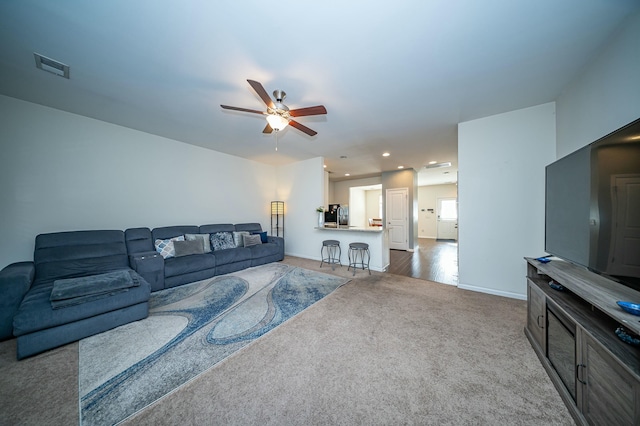 living room with ceiling fan and dark colored carpet