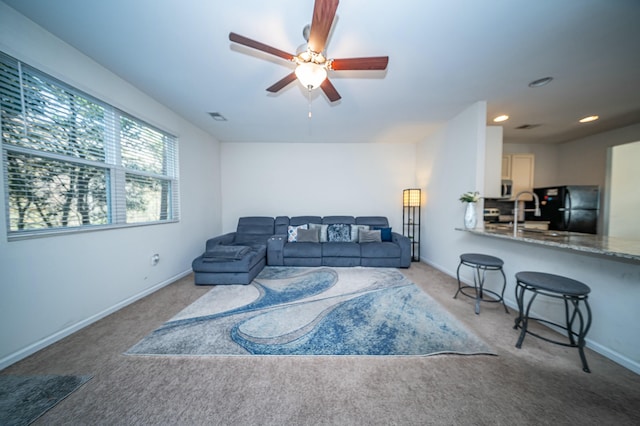 living room featuring ceiling fan, light colored carpet, and sink