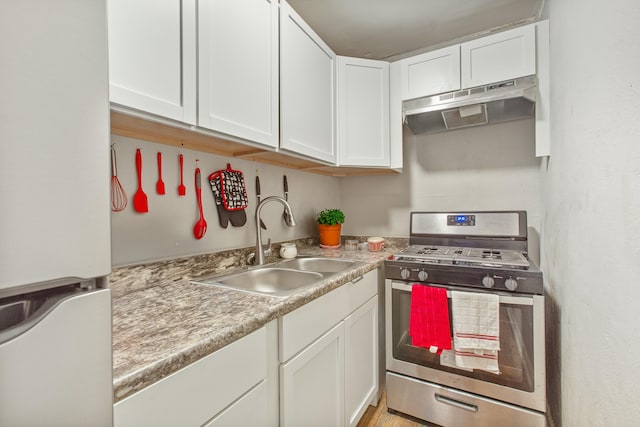 kitchen with white cabinetry, stainless steel range with gas cooktop, sink, and white refrigerator