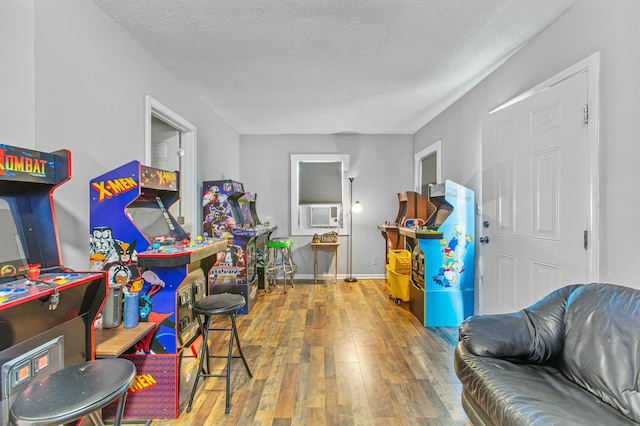 playroom featuring cooling unit, wood-type flooring, and a textured ceiling