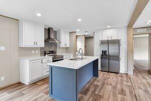 119 Silver King Ave, Cross, SC 29436 - kitchen with light wood-style floors, light countertops, wall chimney exhaust hood, a sink, and appliances with stainless steel finishes