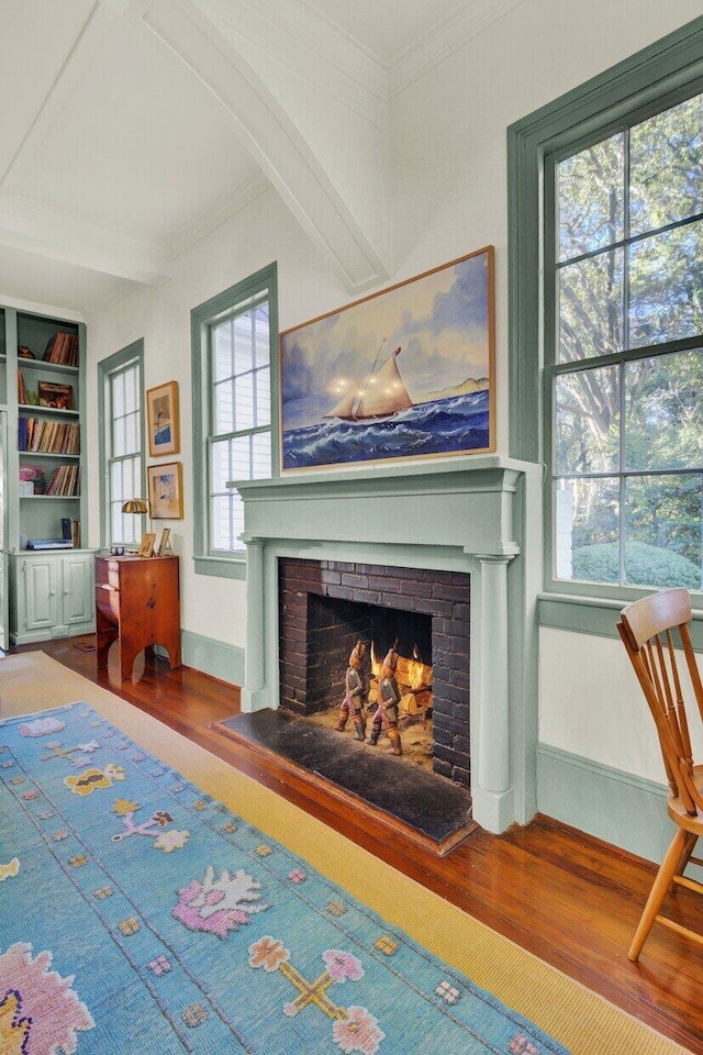 interior space featuring a fireplace, hardwood / wood-style flooring, built in features, and ornamental molding