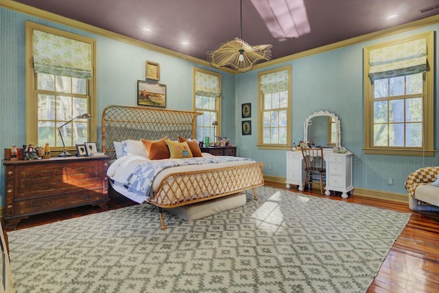 bedroom featuring wood-type flooring, crown molding, and multiple windows