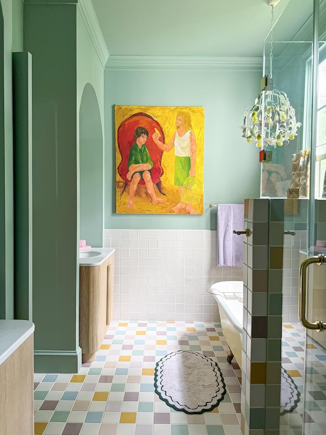 bathroom featuring a shower with door, vanity, tile walls, and ornamental molding