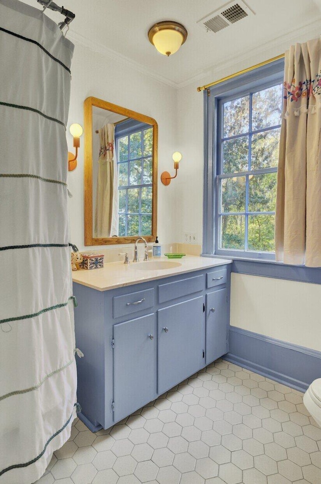 bathroom with toilet, vanity, and ornamental molding