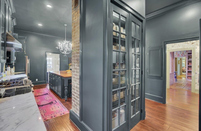 interior space featuring a chandelier, french doors, crown molding, and hardwood / wood-style floors