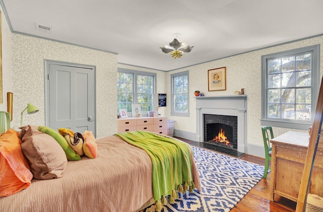 bedroom with hardwood / wood-style floors, crown molding, and multiple windows