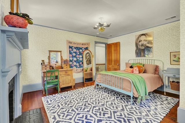 bedroom featuring crown molding, dark hardwood / wood-style floors, and an inviting chandelier