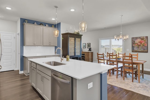 kitchen featuring stainless steel dishwasher, gray cabinets, sink, and an island with sink