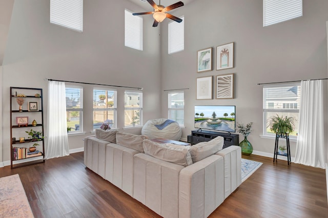 living room featuring ceiling fan, a towering ceiling, and dark wood-type flooring