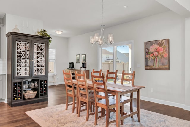 dining area with a healthy amount of sunlight, a notable chandelier, and dark hardwood / wood-style flooring