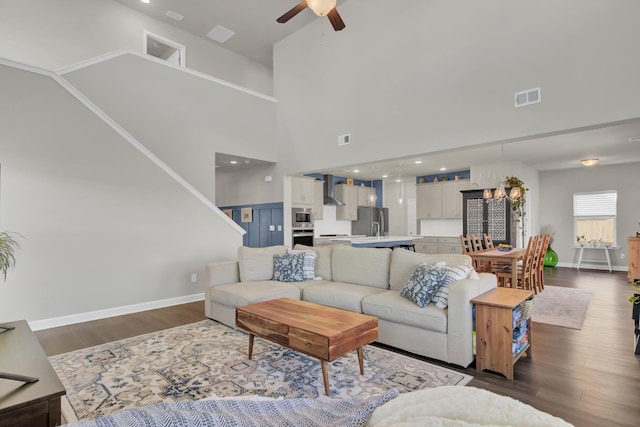 living room with a high ceiling, dark hardwood / wood-style floors, and ceiling fan