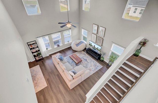 living room featuring ceiling fan, a towering ceiling, and dark wood-type flooring