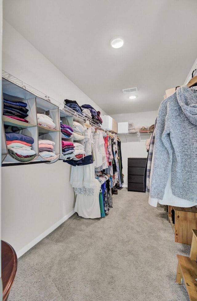 walk in closet featuring light colored carpet