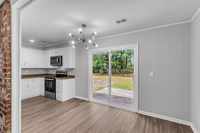 kitchen with dark countertops, stainless steel appliances, light wood finished floors, and a textured ceiling